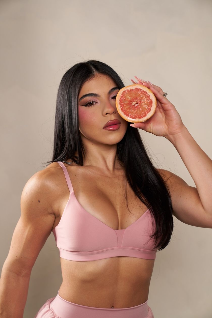 Diana Sosa holding a grapefruit slice beside her face