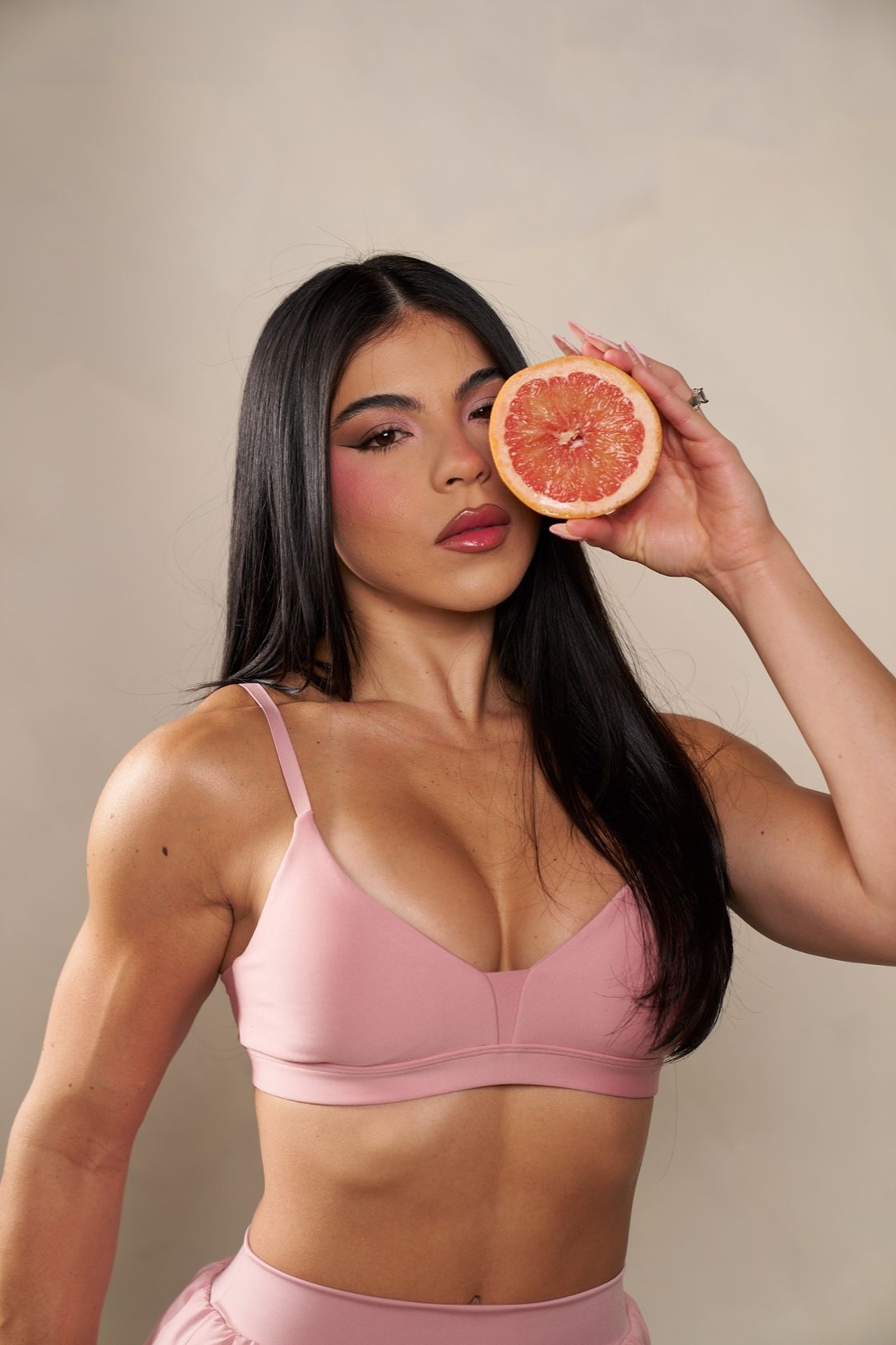 Diana Sosa holding a grapefruit slice beside her face